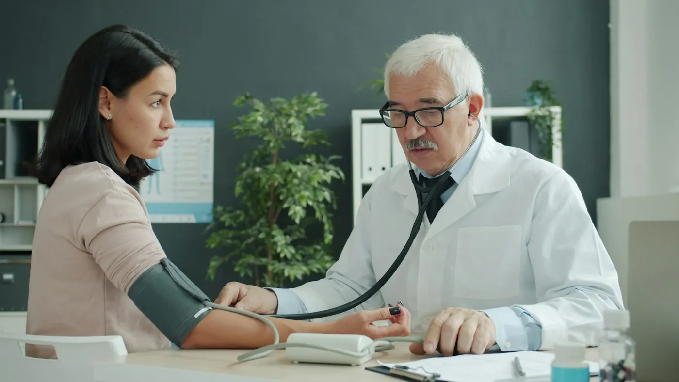 Médico aferindo a pressão arterial de uma candidata durante o exame admissional