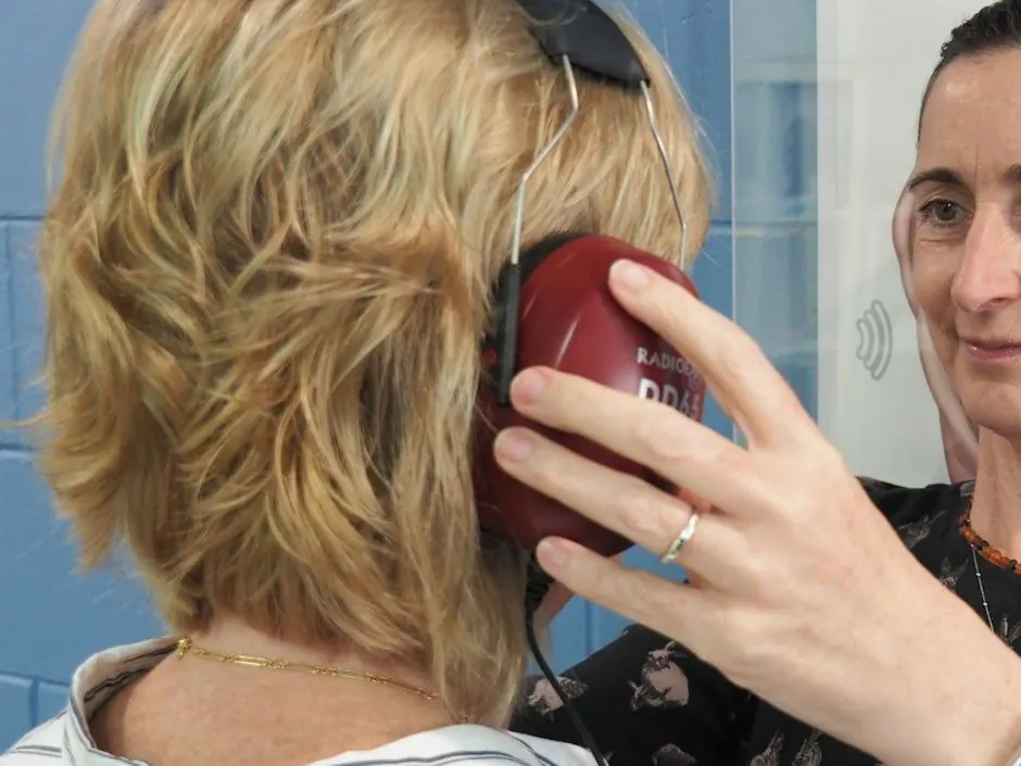 Profissional posicionando o fone audiométrico na orelha da colaboradora durante a audiometria