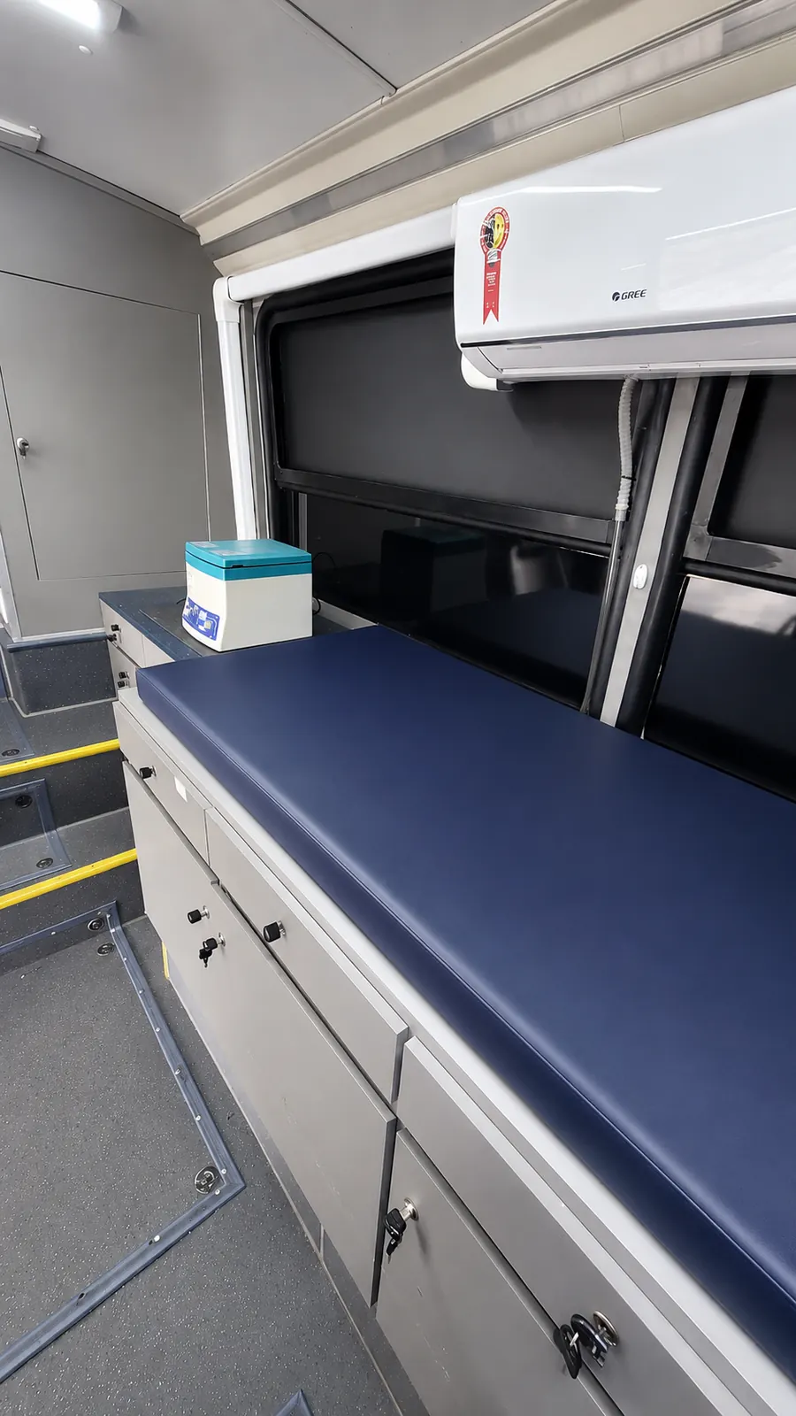 Maca de atendimento e armários de equipamentos dentro do ônibus clínica