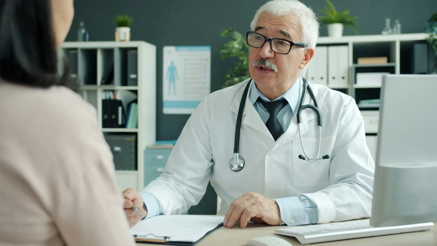 Médico do trabalho conversando com colaboradora durante consulta de acompanhamento periódico
